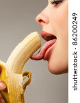 Close-up female mouth licking peeled banana - stock photo