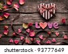 stock photo : Word Love with Heart shaped Valentines Day gift box on old vintage wooden plates. Sweet holiday background with rose petals, small hearts, curved ribbon.